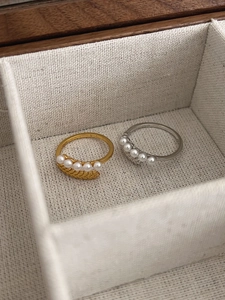Dettaglio di anelli S925 in oro e argento con cinque perle e trama a spiga di grano