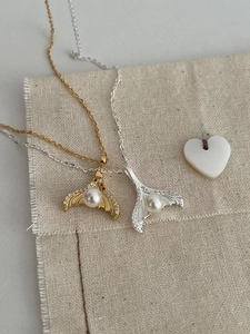 Macro view of gold and silver mermaid tail necklaces with elegant pearls and crystals