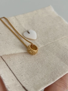 Close-up of golden cylinder pendant with star pattern on elegant woven chain