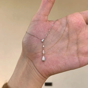 Dettaglio della collana argentata con pendenti a goccia e cristalli su una catena fine