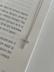 Macro shot of 925 sterling silver cross pendant with cubic zirconia on a book page