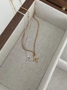 Detailed shot of gold and silver S925 four-point star pendants on beaded satellite chains