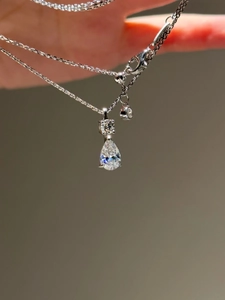 Macro shot of silver pear-shaped teardrop pendant and fine chain with high brilliance