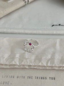 Detailed shot of S925 silver flower ring with pink heart stone on beige linen bag