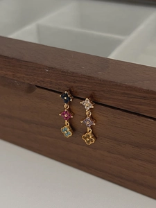 Détail des boucles d'oreilles trèfle à trois couches colorées sur boîte en bois