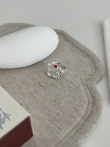 Macro view of S925 silver hollow flower ring with red gemstone and adjustable band