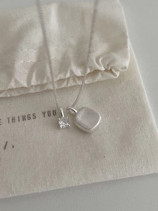 Macro shot of S925 sterling silver square pendant with zircon stone and brushed finish chain