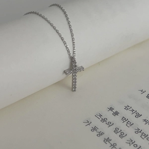 Elegant 925 sterling silver cross necklace with zircons draped over a book page