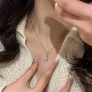 Elegant silver chain necklace featuring double teardrop crystal pendants on white knitwear
