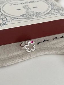 Close-up of S925 silver flower ring with red heart gemstone and hammered texture