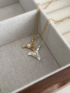 Close-up of gold and silver mermaid tail necklaces with white pearls and zircons