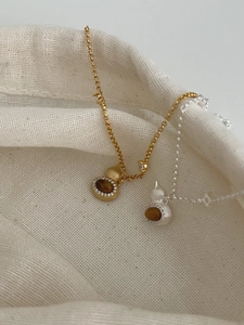 Detail of S925 silver gourd pendants with tiger eye stone and zircons on linen