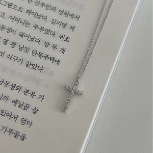 925 silver cross necklace with sparkling zircons on an O-chain over a book