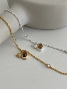 Macro view of gold and silver S925 bracelets featuring tiger eye stone gourd pendants