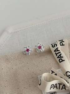 Detail of flower stud earrings featuring red center stones and sparkling white petals