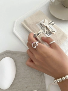 Detail of S925 silver hollow flower ring and matching beaded bracelet on a neutral background