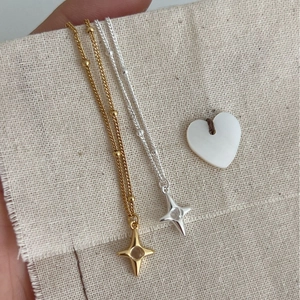 Minimalist S925 sterling silver star necklaces in gold and silver on linen fabric