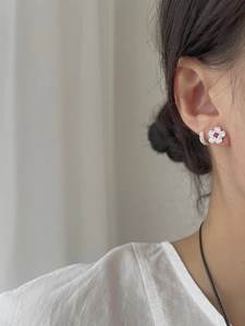 Detailed view of floral stud earring with pink gemstone and crystal hoop on ear