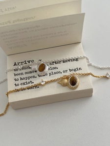 Detailed close-up of tiger eye stone gourd pendants on gold and silver bracelets