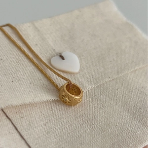 Retro matte gold cylinder necklace with star engraving on beige linen fabric