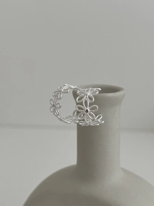 Detailed close-up of S925 silver daisy lace earrings displayed on a matte ceramic vase