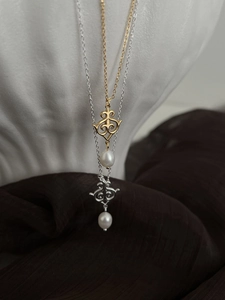 Detail of dual S925 silver and gold tone necklaces with freshwater pearls on satin