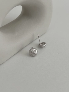 Macro view of brushed silver four-leaf clover stud earrings with sparkling zircon