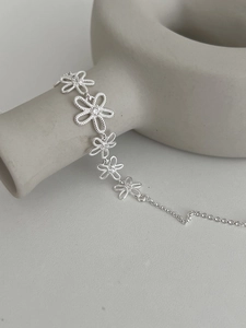 Detailed view of silver hollow flower bracelet with adjustable chain on grey ceramic stand