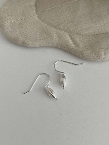 Macro shot of silver S925 earrings with striped olive-shaped pendants and hook closure
