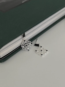 Detailed macro view of silver hollow window-pattern earrings with black gemstones