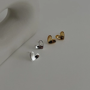 Detailed view of polished 3D heart stud earrings in silver and gold finishes