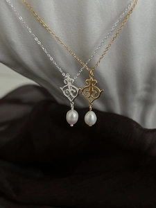 Detail of ethnic engraved gold and silver pendants with teardrop pearls on S925 chains