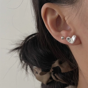 S925 sterling silver minimalist heart stud earrings worn in a stylish layered style