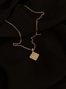 Detail of a vintage golden floral pendant necklace with micro-pave crystals on silk