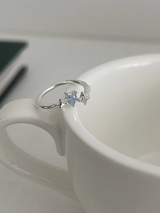 Macro shot of S925 silver star ring with blue gemstone on a white ceramic cup edge
