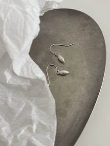 Detailed view of S925 sterling silver shell earrings with textured seed pendant on a tray