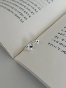 Close-up of S925 silver bypass ring with brushed hydrangea petals and blue zircon