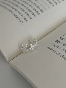 Détail d'une bague papillon en argent S925 avec zircons posée sur un livre ouvert