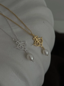 Detailed close-up of vintage hollow scroll pendants with drop-shaped white pearls