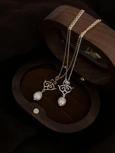 Detail of gold and silver baroque pearl necklaces displayed on a wooden jewelry box