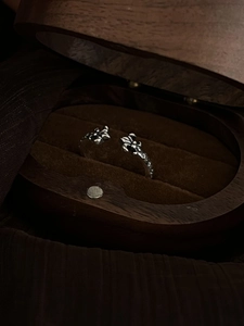 Detailed close-up of retro silver open ring with cross floral relief on velvet padding