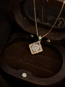 Detail of a gold-plated square pendant necklace with glittering crystals in a jewelry box