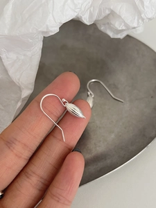 Macro detail of S925 sterling silver shell drop earrings with textured olive pendants