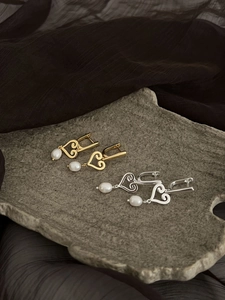 Détail de boucles d'oreilles cœur en argent et or avec perles d'eau douce pendantes