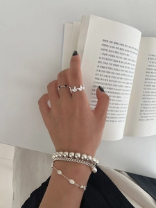 Détail d'une bague papillon en argent S925 et bracelets superposés avec perles