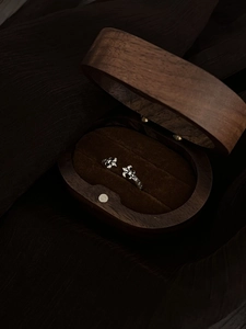 Close-up of vintage silver fleur-de-lis open ring in a luxury dark wood jewelry box