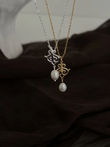 Close-up of vintage hollow pendants with teardrop pearls in gold and silver finishes