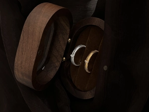 Gold and silver striped rings with zircons displayed in a vintage wooden jewelry box