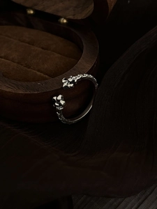Close-up of vintage gothic cross open ring on dark wooden box with fabric background