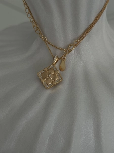 Detail of gold four-leaf clover pendant necklace with brushed texture and zircon stones